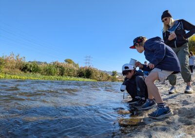 More 3rd graders take water samples from the river as Mrs. Nelson oversees the process.