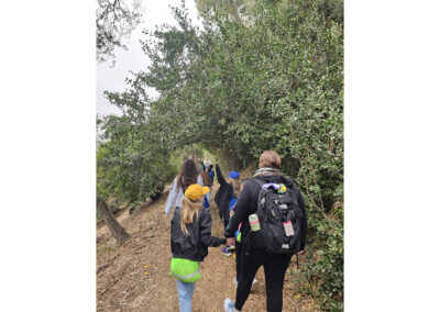 The 4th graders walk hand-in-hand through a tree-lined path.