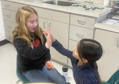 A 5th grade girl high-fives her kindergarten buddy at Para Los Ninos.