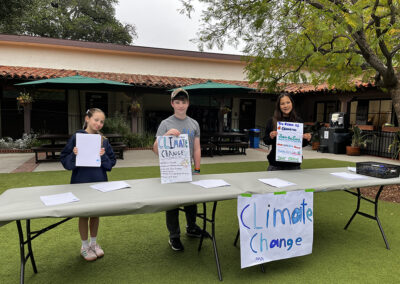 The group of 6th graders who chose Climate Change as their cause for activism pose in front of their booth prepared to make posters to raise awareness.