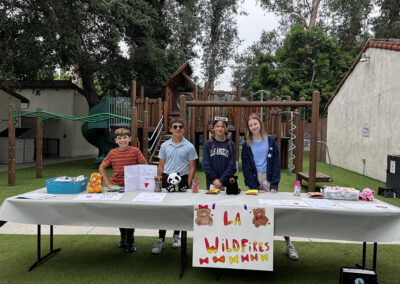 The group of 6th graders who chose LA Wildfires as their cause for activism pose in front of their booth prepared to make inspirational cards and paper bears.