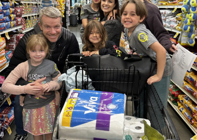 Kindergarteners and parent volunteers pose with a full shopping cart.