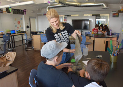 Mrs. Nelson helps two students make cement stepstones for the garden.