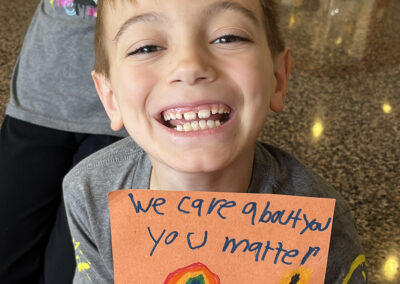 A second-grader poses with his note of encouragement to be delivered with the food.