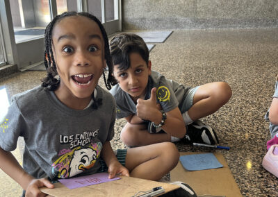 A thumbs up from two second-grade boys working on their notes of encouragement.
